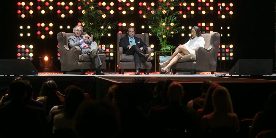 Tom Bozzuto, Toby Bozzuto, & Stephanie Williams seated on a stage & addressing an audience