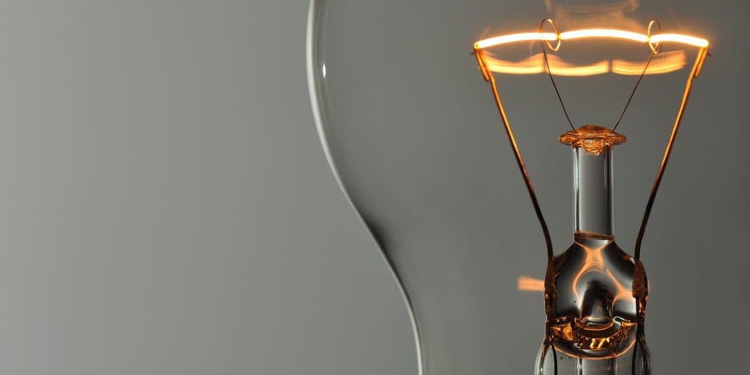 Illuminated light bulb with intricate coils at closeup.