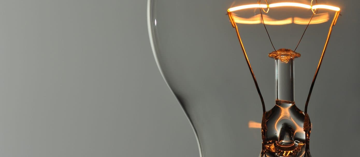 Illuminated light bulb with intricate coils at closeup.