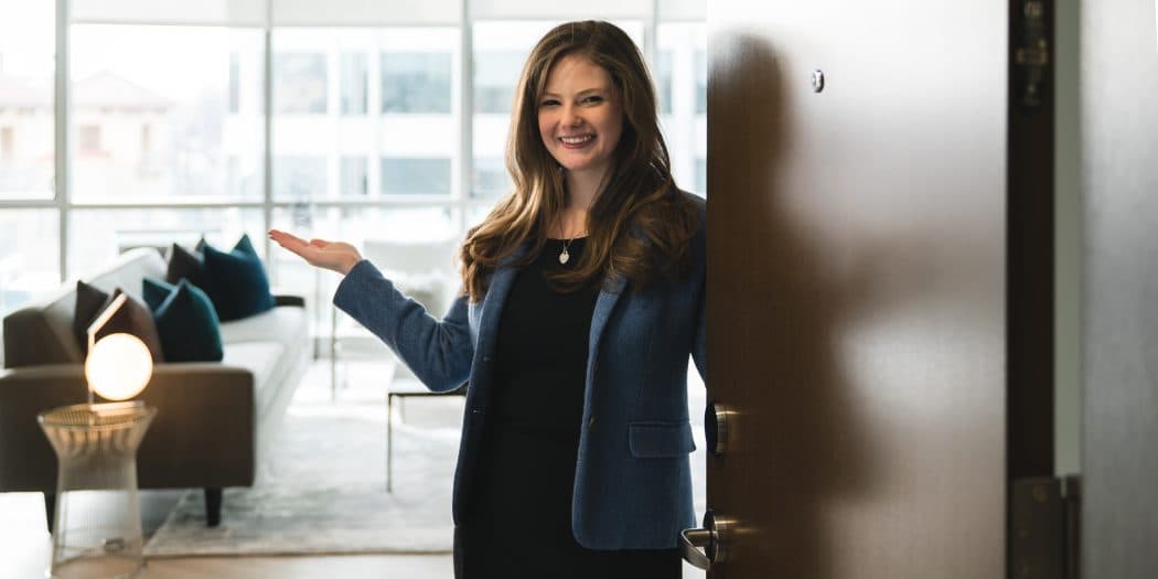 A female Bozzuto executive eagerly awaits behind a door, her hands outstretched in anticipation.