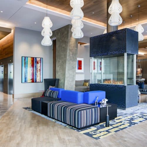 Inviting lobby with open seating, large-screen TVs, and a glass fireplace centerpiece.