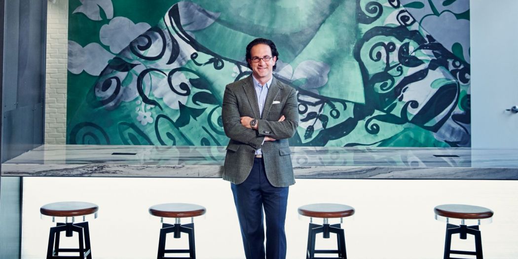 Toby Bozzuto, president and CEO of the Bozzuto Group, posing in front of a mural.