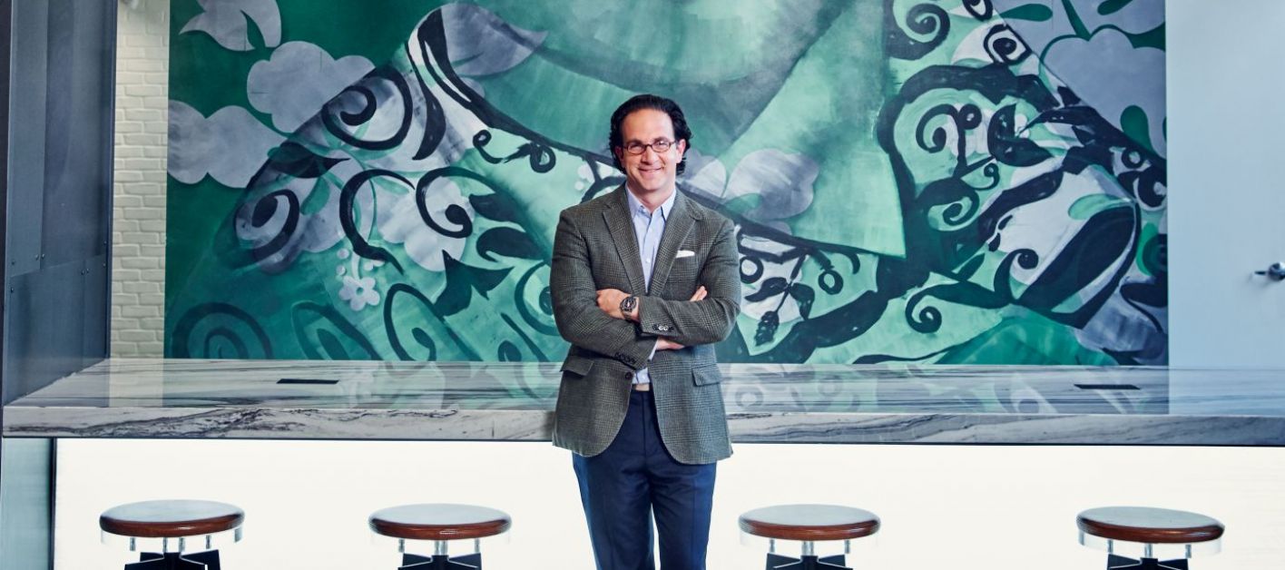 Toby Bozzuto, president and CEO of the Bozzuto Group, posing in front of a mural.