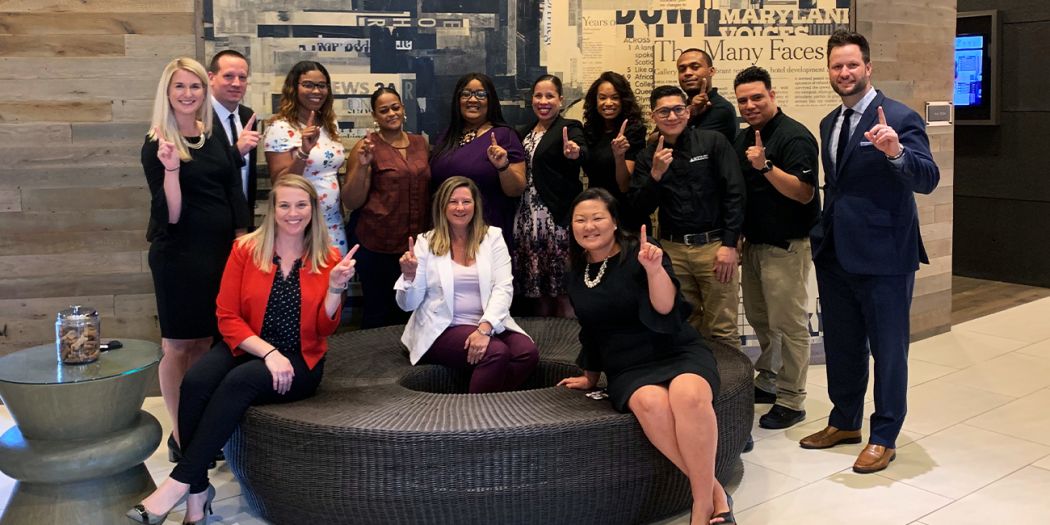 Group of Bozzuto individuals posing with the number 1 finger sign.