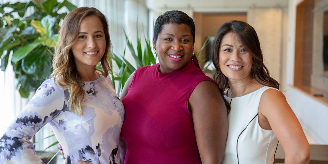 Three women smiling and posing for a photo inside a Bozzuto office.