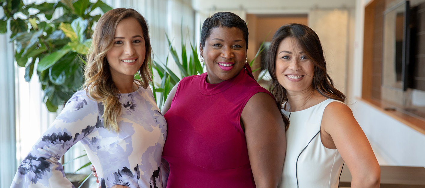 Three women smiling and posing for a photo inside a Bozzuto office.