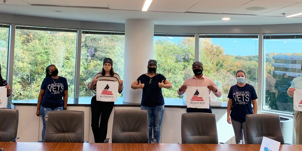 Group of individuals wearing masks and some waving Bozzuto Vets mini-flags.