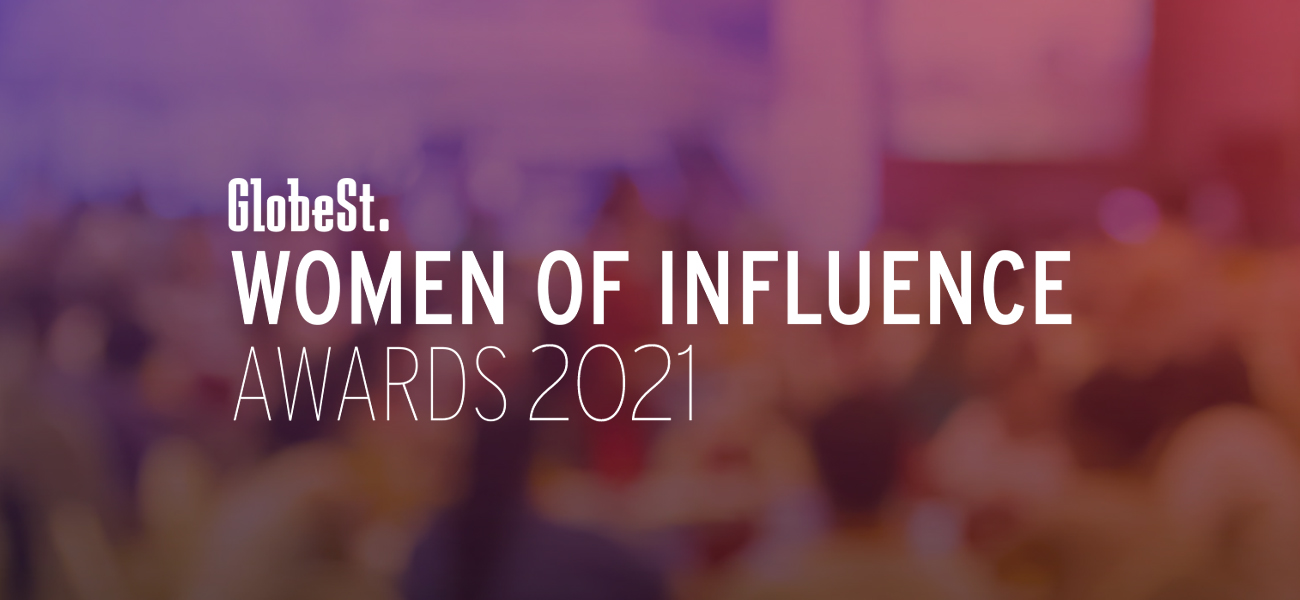 GlobeSt. Women of Influence Awards signage in a purple, blurred backdrop.