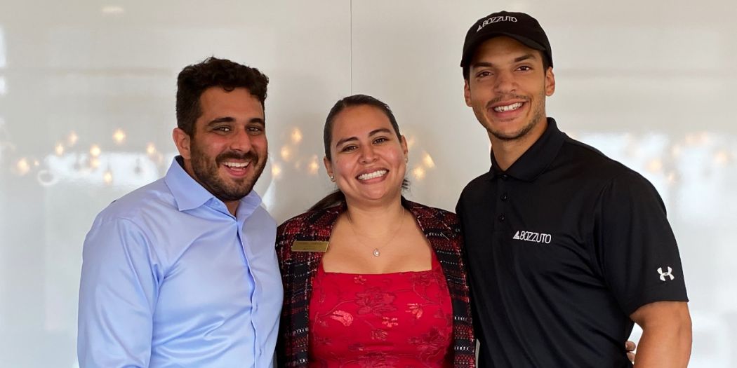 Three individuals from Bozzuto posing happily in front of a white wall.