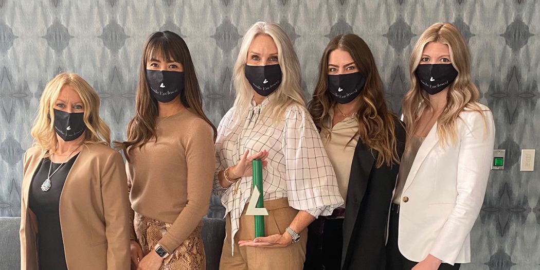 Five Bozzuto female professionals wearing face masks, with one in the middle holding a Bozzuto trophy.