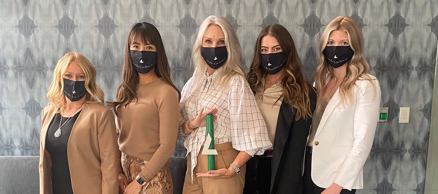 Five Bozzuto female professionals wearing face masks, with one in the middle holding a Bozzuto trophy.