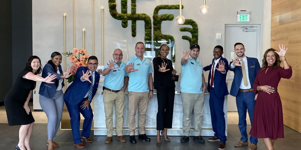 Stephanie Williams posing with Bozzuto professionals, all celebrating with a high five.