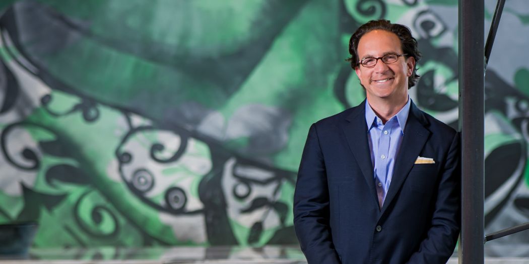 Toby Bozzuto, president and CEO of the Bozzuto Group, posing in front of a mural.