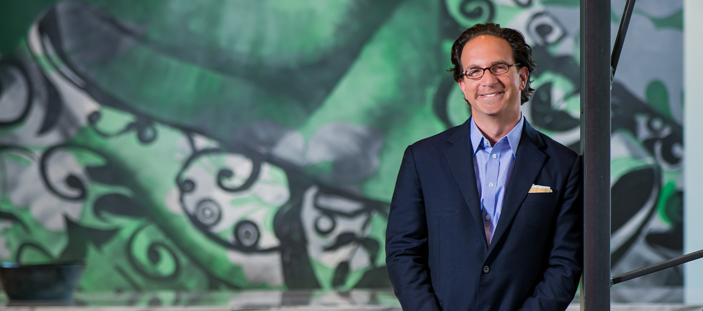 Toby Bozzuto, president and CEO of the Bozzuto Group, posing in front of a mural.