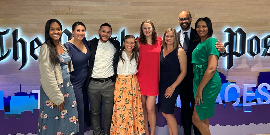 Bozzuto staff members posing in front of the Washington Post signage.