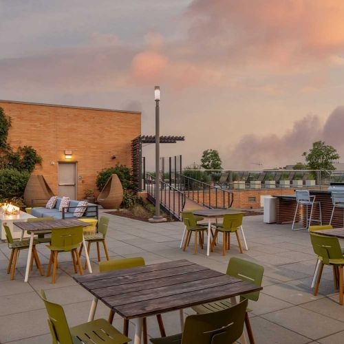 An expansive rooftop sun deck featuring sitting areas and tables for dining