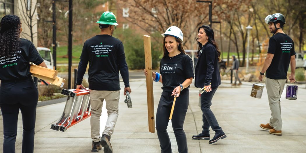 Bozzuto group of people carrying tools, ladder, wood, and paint cans.