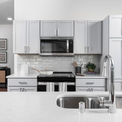 Bright, modern kitchens with polishes quartz countertops against designer backsplashes.
