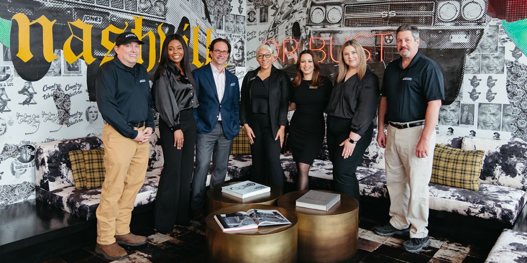 Bozzuto leaders & staff members posing in front of an art wall.