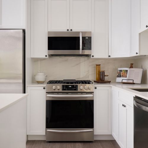 The classic design palette features calacatta backsplash, organic white quartz countertops, white shaker cabinets, and panelized islands