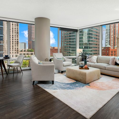A corner apartment living and dining area flooded with natural light from floor-to-ceiling windows.