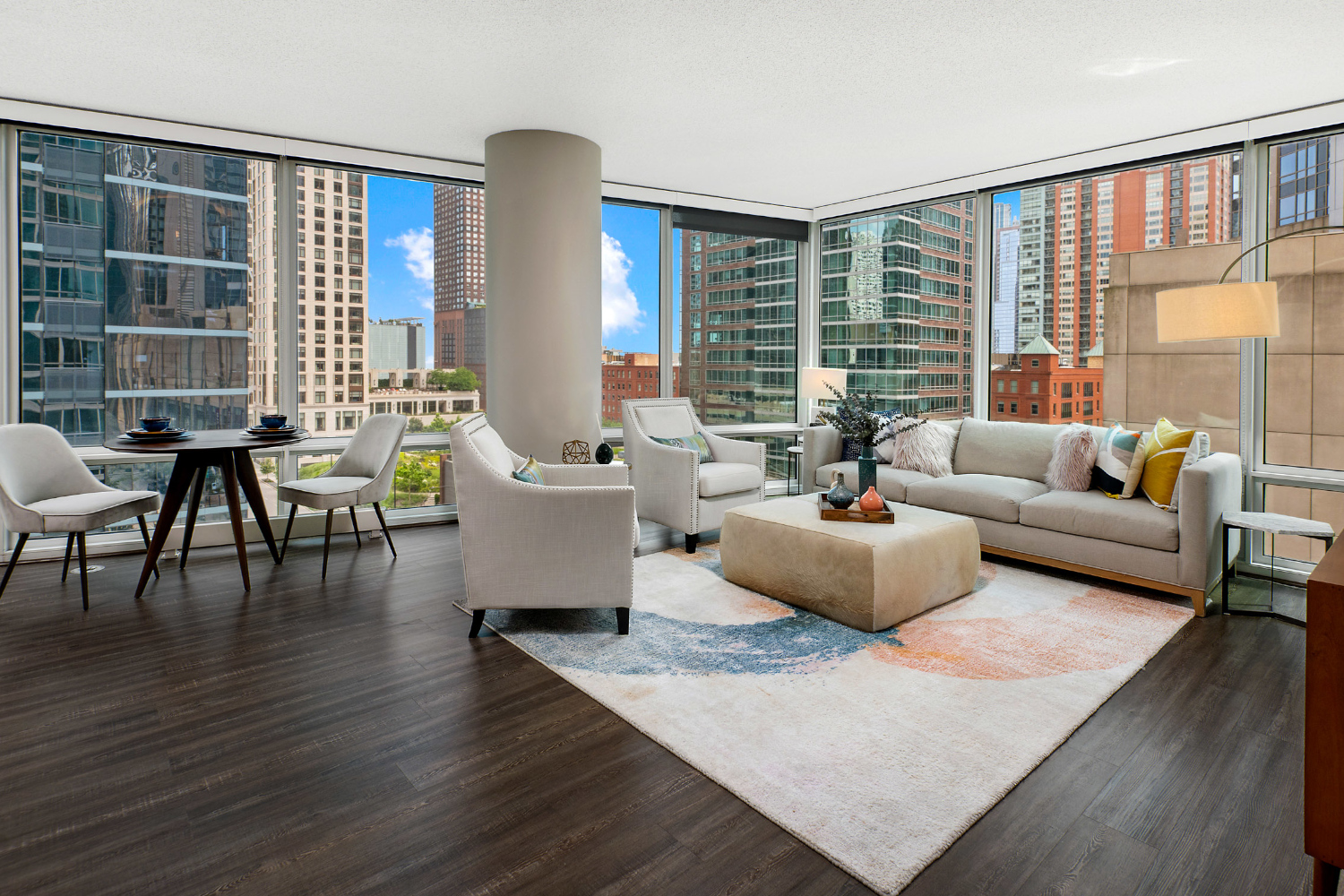 A corner apartment living and dining area flooded with natural light from floor-to-ceiling windows.