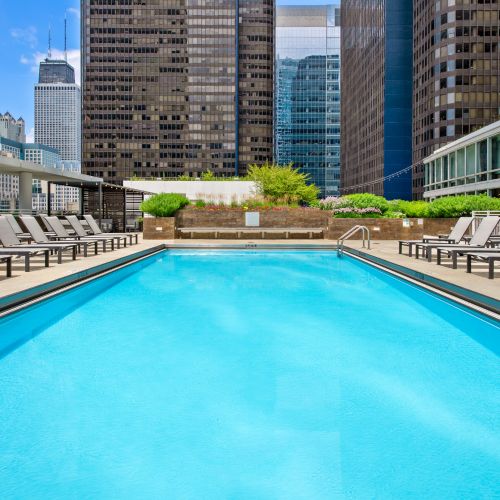 Wide angle of Atwater's outdoor sundeck featuring a resort-style pool and lounge seating with the cityscape in the background.