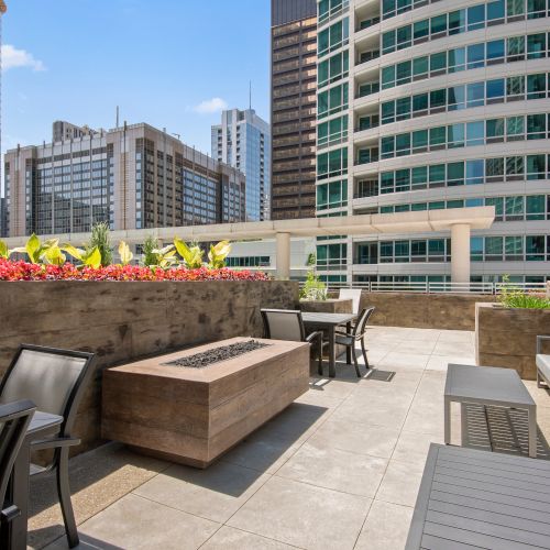 Close up of Atwater's sundeck featuring lounge seating and patio furniture with foliage and the cityscape in the background.