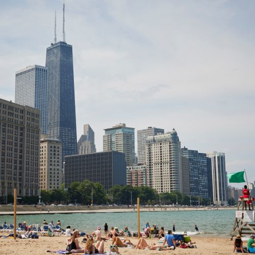 Wide angle of Ohio Street Beach connecting to Lake Michigan with Chicago's Lakefront Trail and cityscape in the background.