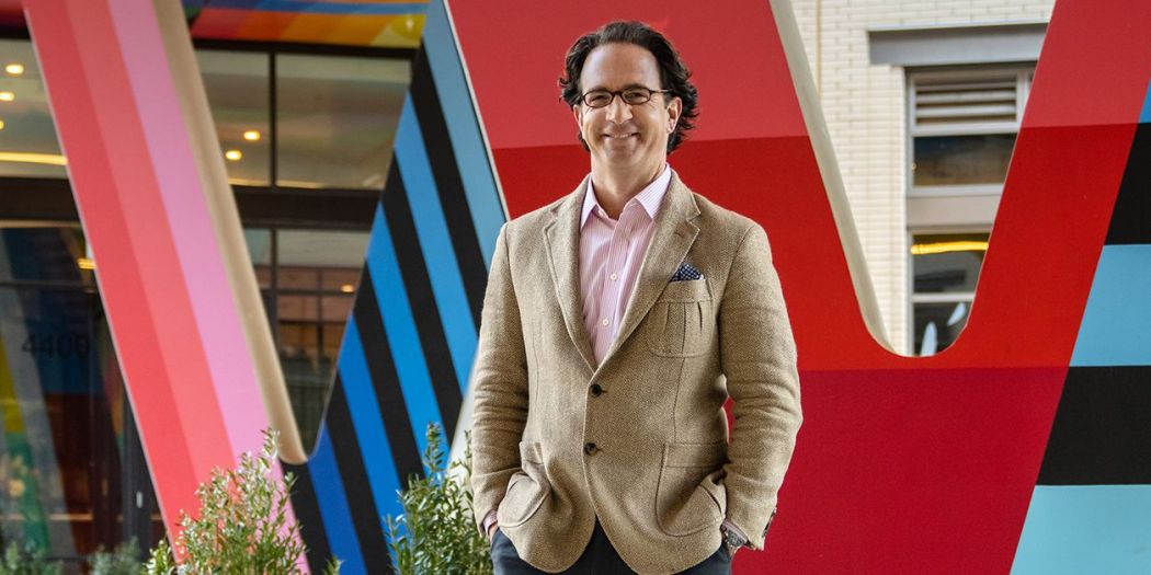 Toby Bozzuto, President & CEO of the Bozzuto Group, standing in front of a big W sign of a building.