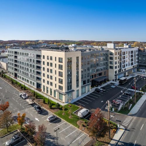 Arial view of large multi-story apartment complex with parking and surrounding roads