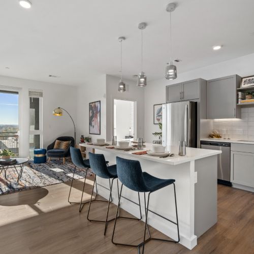 Open kitchen and living area with gray cabinets, barstools, and large windows with view