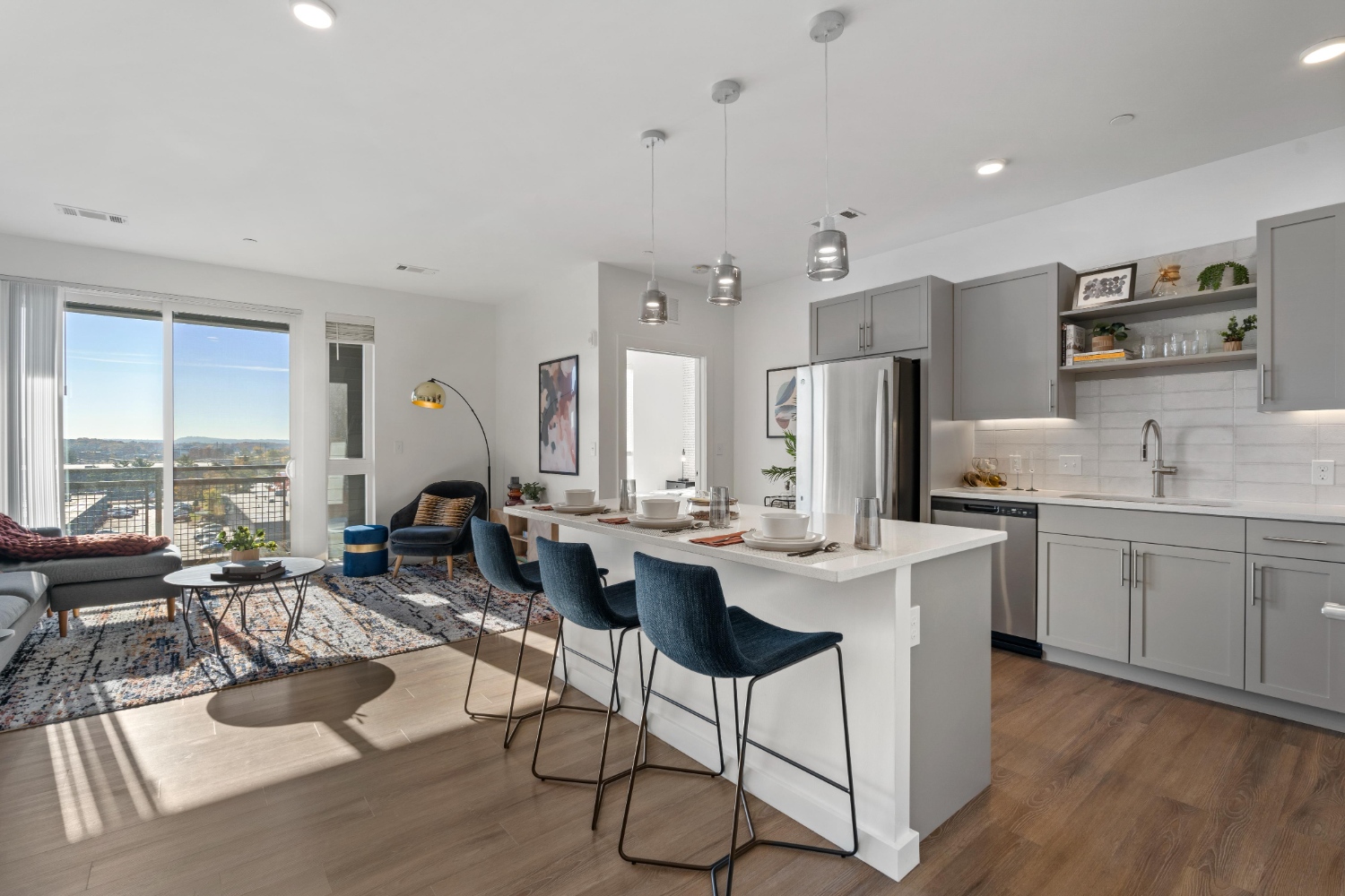 Open kitchen and living area with gray cabinets, barstools, and large windows with view