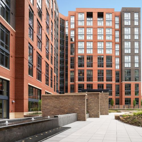 Brick apartment courtyard with water feature, stone privacy walls, and modern landscaping