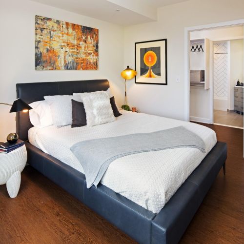 Modern bedroom with upholstered bed, abstract art, and view into walk-in closet