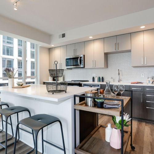 Modern kitchen with two-tone cabinets, island seating, bar cart, and stainless appliances