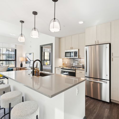 Bright modern kitchen with light wood cabinets, stainless appliances, and island seating
