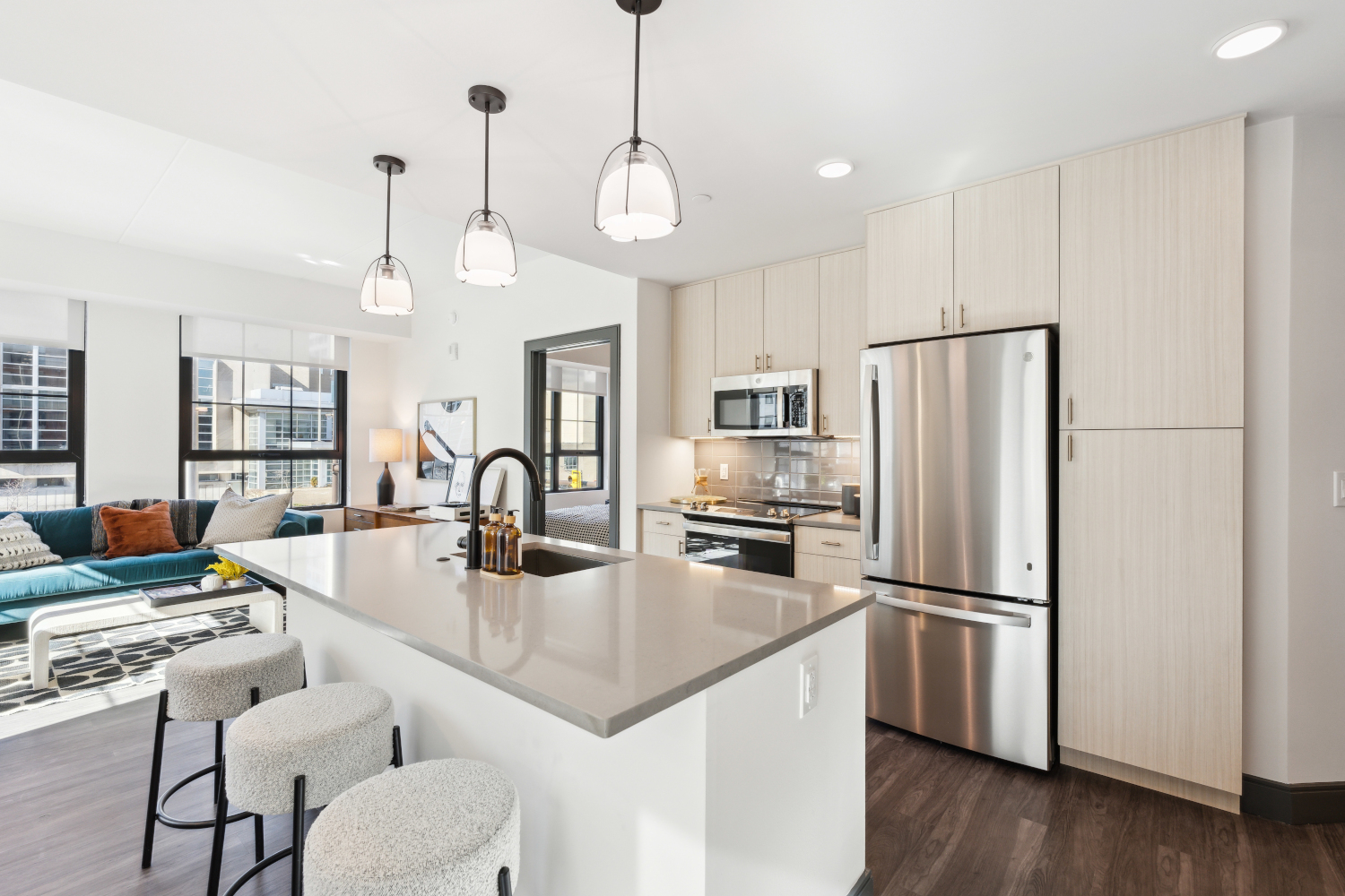 Bright modern kitchen with light wood cabinets, stainless appliances, and island seating