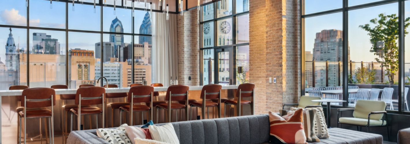 Rooftop lounge with bar, seating and views of city	