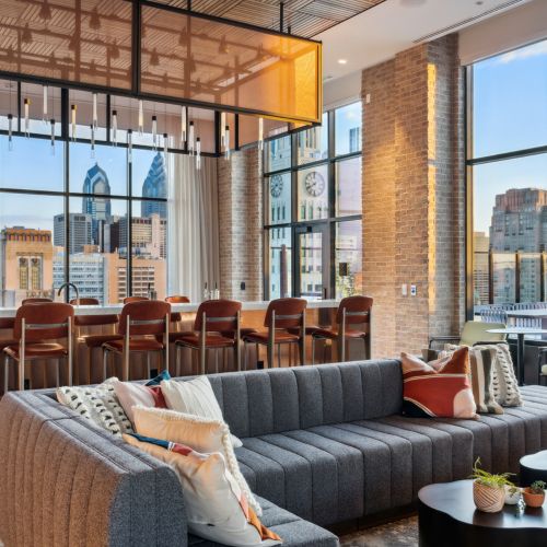 Rooftop lounge with bar, seating and views of city	