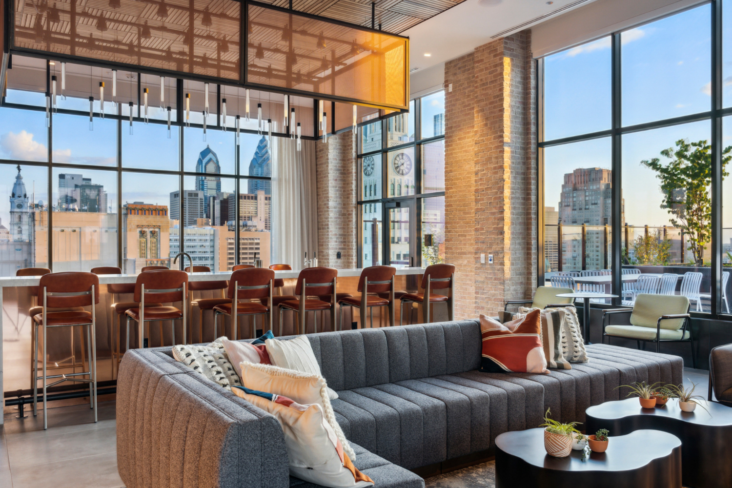 Rooftop lounge with bar, seating and views of city	