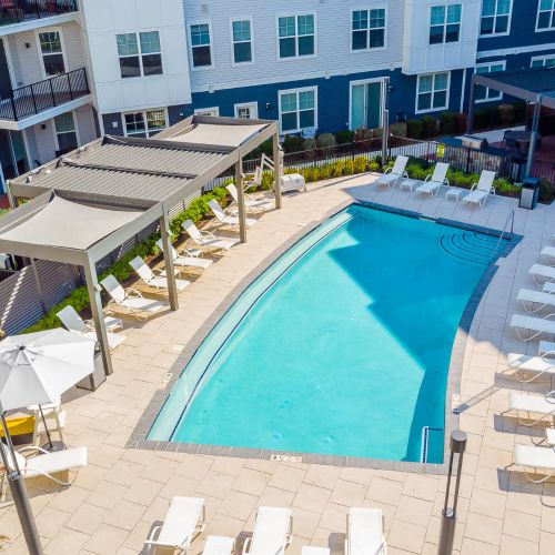 Pool with lounge chairs and view of apartments	