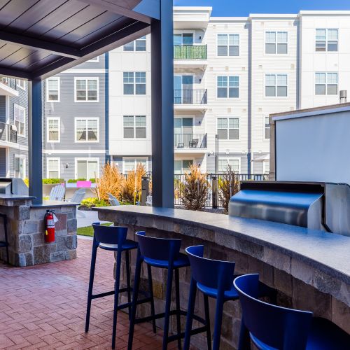 Outdoor bar seating near grills with view of screen	