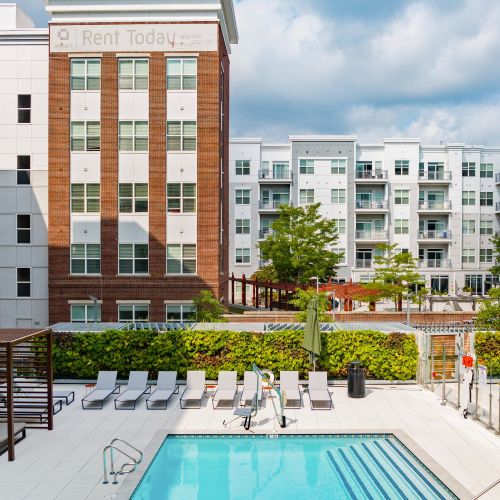 Outdoor apartment pool with lounge chairs, cabana, and view of courtyard and buildings