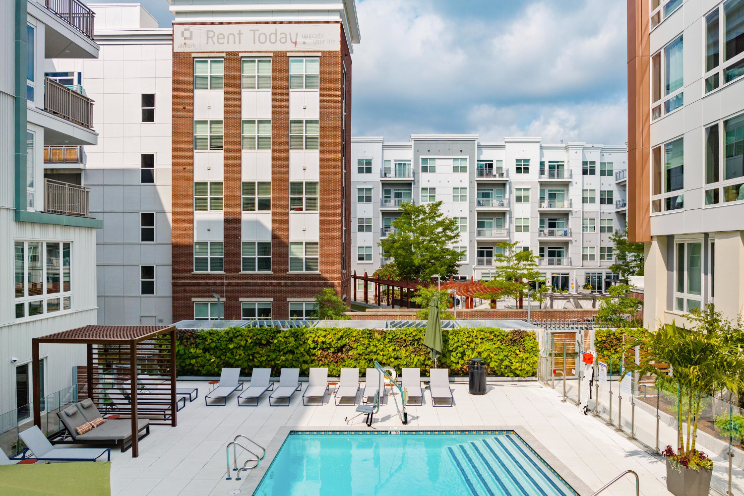 Outdoor apartment pool with lounge chairs, cabana, and view of courtyard and buildings