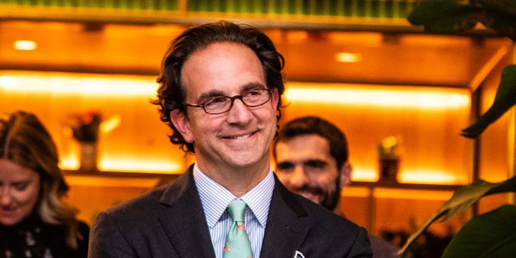 CEO Toby Bozzuto smiling at the camera with some people in his background.