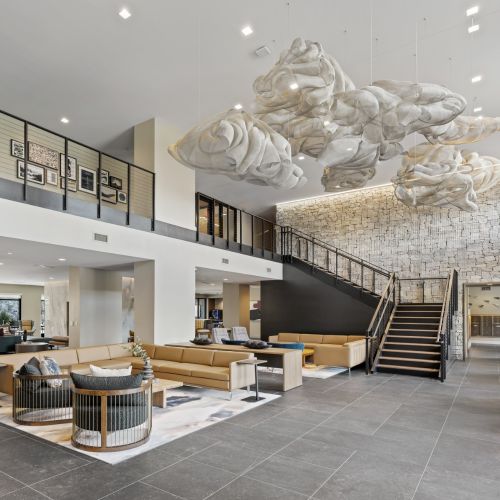 Spacious lobby with sculptural ceiling art, stone accent wall, and modern lounge seating