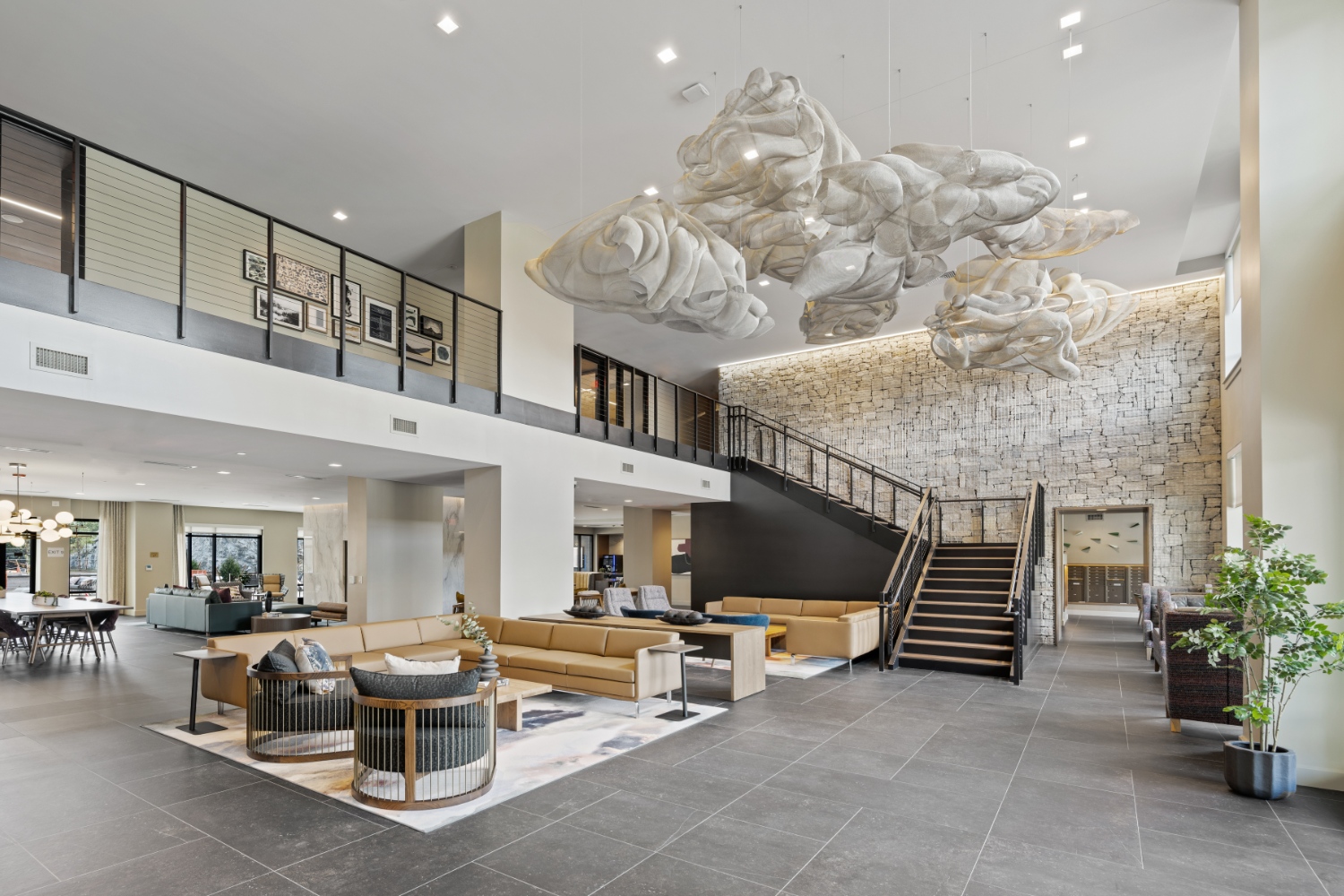 Spacious lobby with sculptural ceiling art, stone accent wall, and modern lounge seating