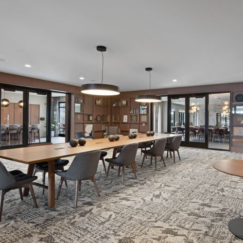 Modern meeting room with long wood table, pendant lights, and built-in bookshelves
