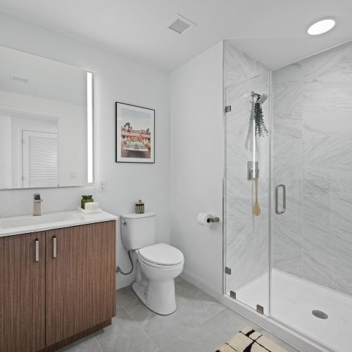 Studio bathroom with a lit mirror and shower.